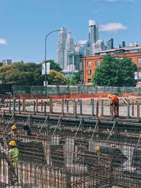 Men working at construction site in city against sky