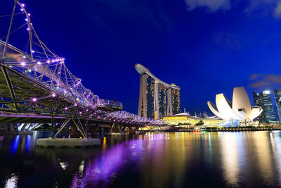 Illuminated city by river at night