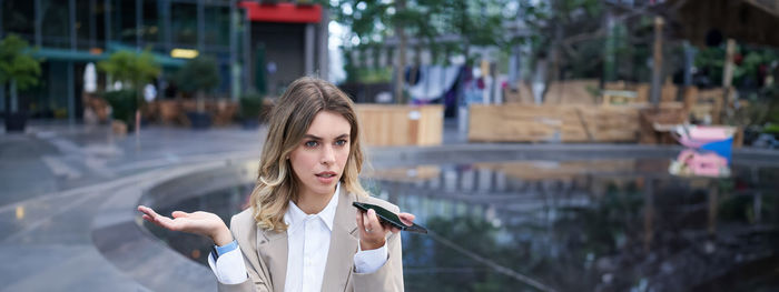 Portrait of smiling young woman standing in city