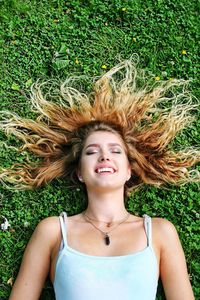 Portrait of a smiling young woman lying down on field