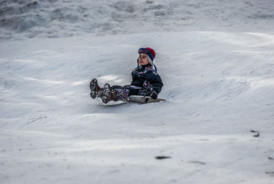 Boy tobogganing on snowy field