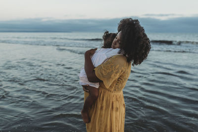 Side view of mother and daughter hugging in the ocean