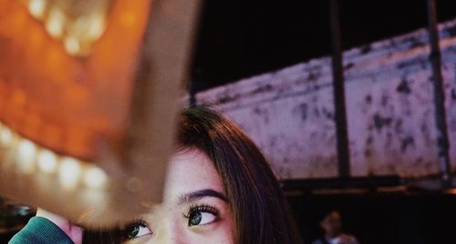 Close-up of young woman looking away at night