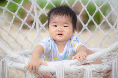 Portrait of cute baby girl sitting on fence