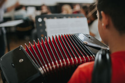 Rear view of man playing accordion in music school