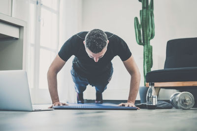 Sporty man working out and trains at home. fit boy doing exercises on the mat in the living room. 