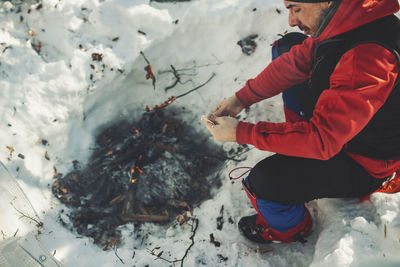 Man preparing meat in bonfire during winter