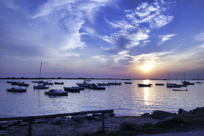 Sailboats moored in sea at sunset