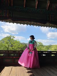 Rear view of woman standing against pink sky