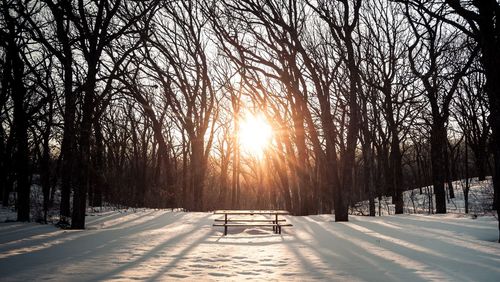 Snow covered field against sky during sunset