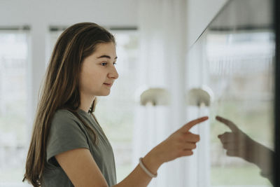 Side view of girl using smart tv while standing at home