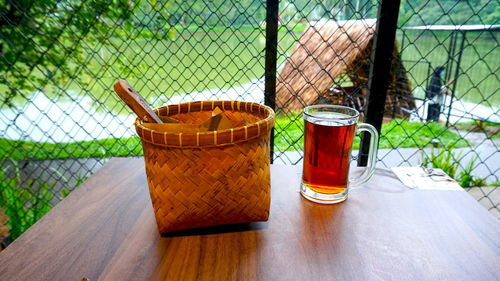 Close-up of drink in basket on fence