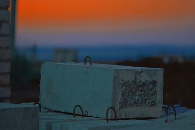 Close-up of old metal retaining wall against sky during sunset