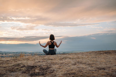 A woman meditates outside at sunset, finding relaxation and inner peace in nature