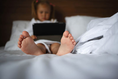 Girl using digital tablet sitting on bed