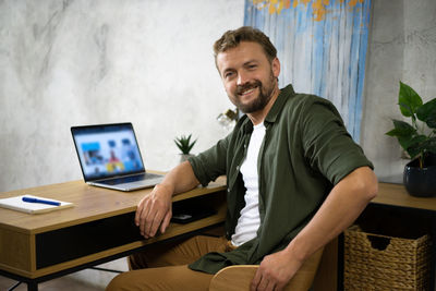 Portrait of young man using laptop at home