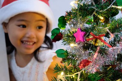 Cute girl looking at christmas tree at home