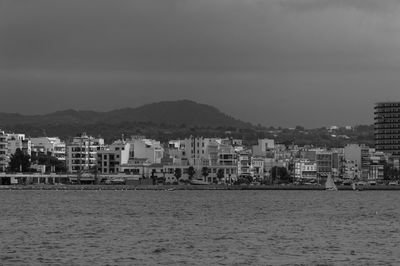 Sea by city buildings against sky