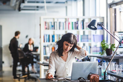 Young woman using phone while sitting on table