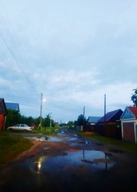 Road by buildings against sky