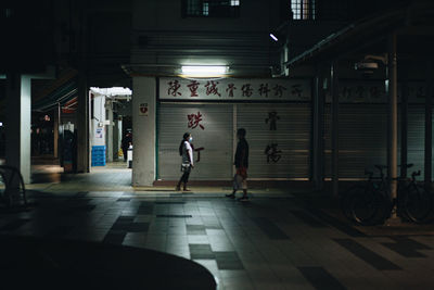 People walking on illuminated street at night