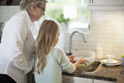 Grandmother and granddaughter washing vegetables in kitchen