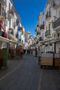 Street amidst buildings against blue sky