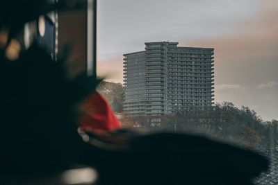 Close-up of buildings against sky seen through glass window