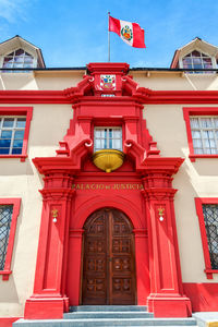 Low angle view of peruvian flag on courthouse against sky