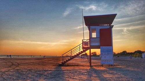 Lifeguard hut on beach against sky during sunset