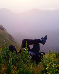 Man relaxing on field against sky