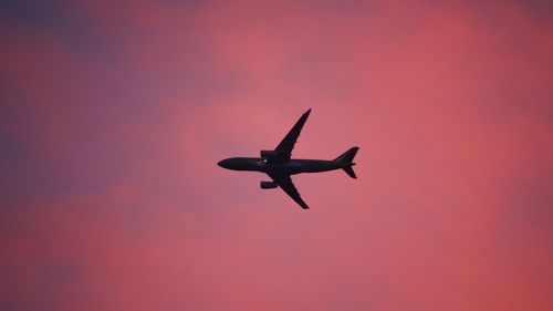 Low angle view of silhouette airplane against sky during sunset