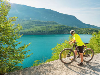 Young biker looking over molveno lake from gravel trail around.  active holiday in dolomites, italy