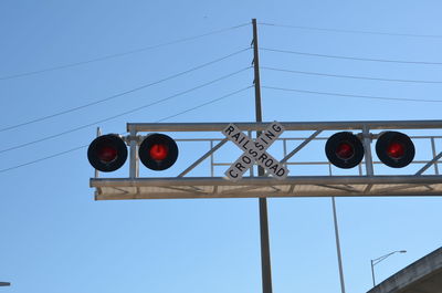 Low angle view of road sign against clear blue sky