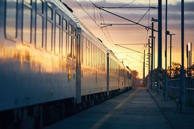 Railway at sunrise. passenger train leaving from railroad station.