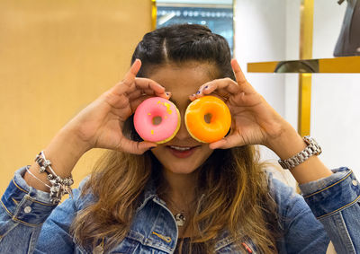 Close-up of woman holding donuts in front of eyes