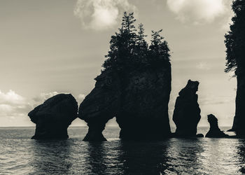 Silhouette rocks on sea against sky