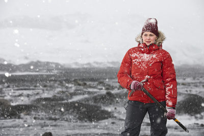 Woman standing and holding ice axe close to glacier in iceland