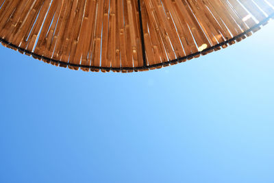 Low angle view of wet glass against clear blue sky