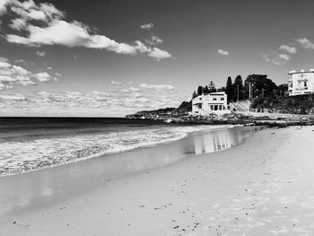 Scenic view of beach by buildings against sky