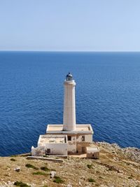 Lighthouse by sea against sky