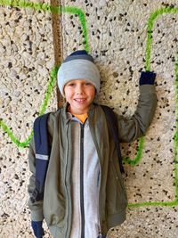 Portrait of smiling girl standing against wall