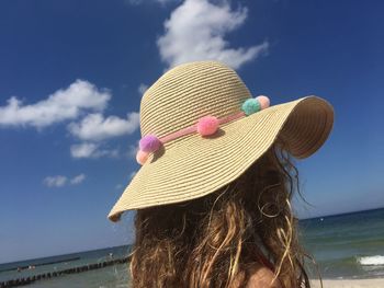 Woman with hat on beach against sky