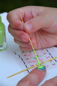 Cropped hand applying nail art on finger of woman