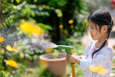 Close-up of cute girl with garden hose