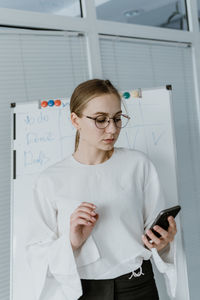 Young business woman, speaker coach drawing on white board and having online meeting in office