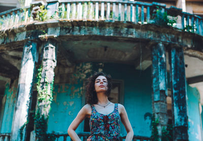 Woman looking up while standing against built structure