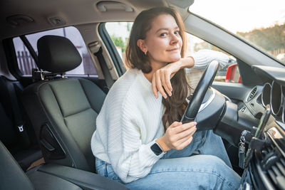 Young woman using mobile phone while in car