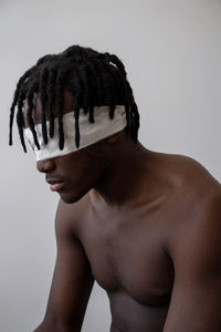 Portrait of shirtless young man against white background