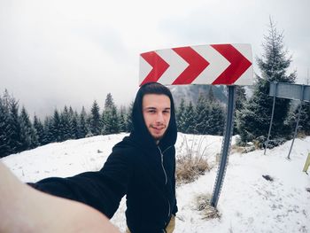 Portrait of smiling man standing on snow covered landscape